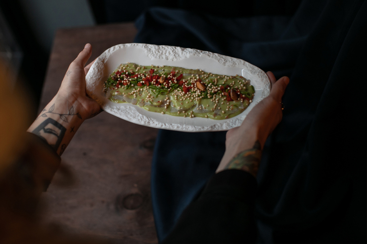 Tiradito peruano vegano de láminas de champiñón con salsa de ají triturado y maíz frito.