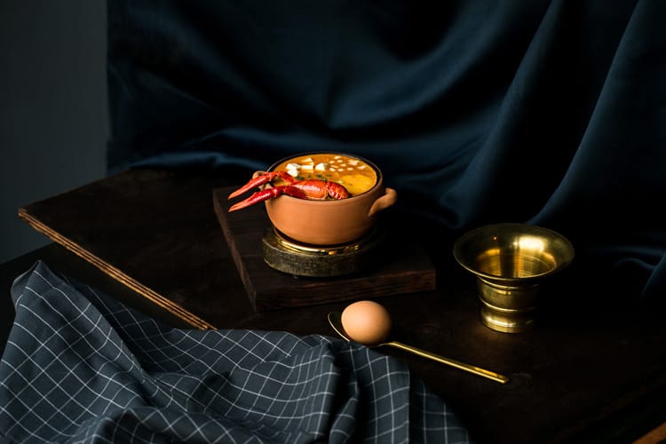 Chupe peruano de camarón en bol de barro sobre mesa de madera oscura.