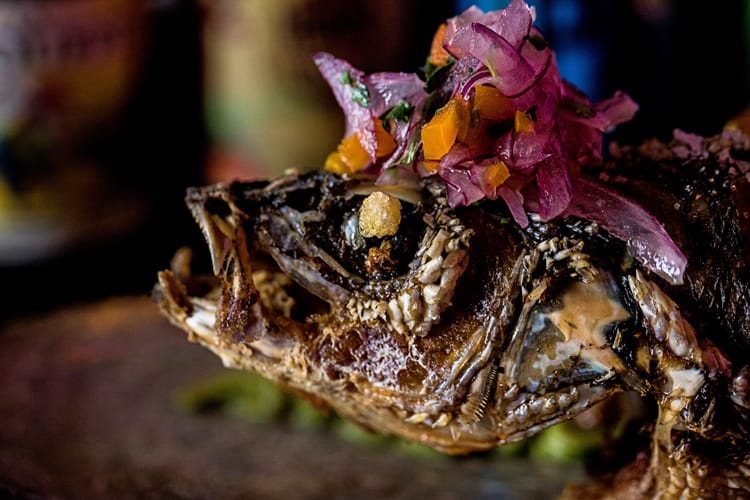 Cabeza de lubina frita con ají y cebolla morada al estilo peruano.