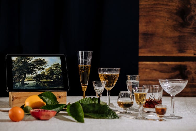 Despliegue de copas de alcohol sobre mesa con decoración vegetal y un ipad.