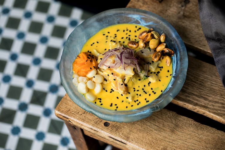 Plato de ceviche peruano vegano de palmito sobre mesa de madera oscura.