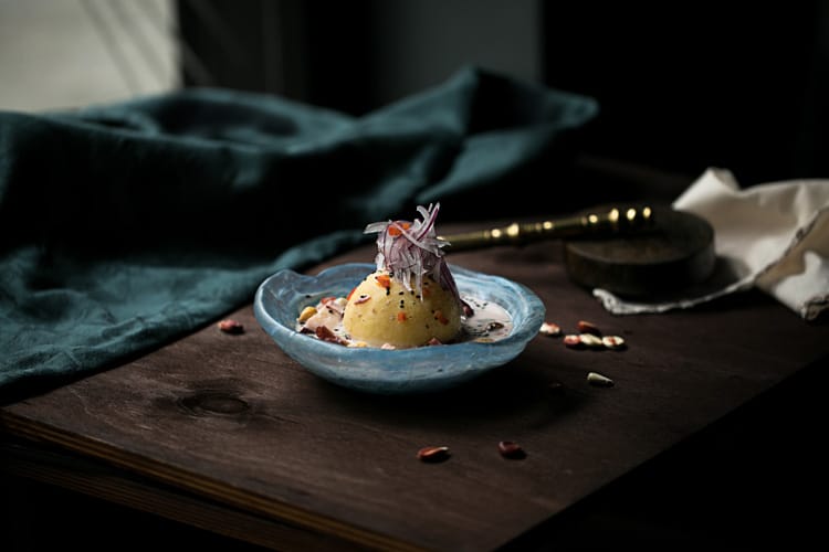 Plato de causa peruana con papa amarilla y cebolla morada sobre mesa de madera oscura.